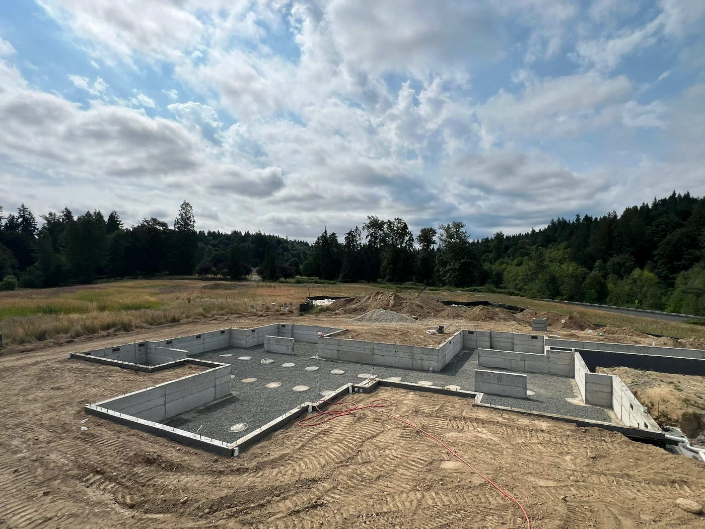Poured concrete crawlspace foundation with gravel base and interior pier pads ready for framing