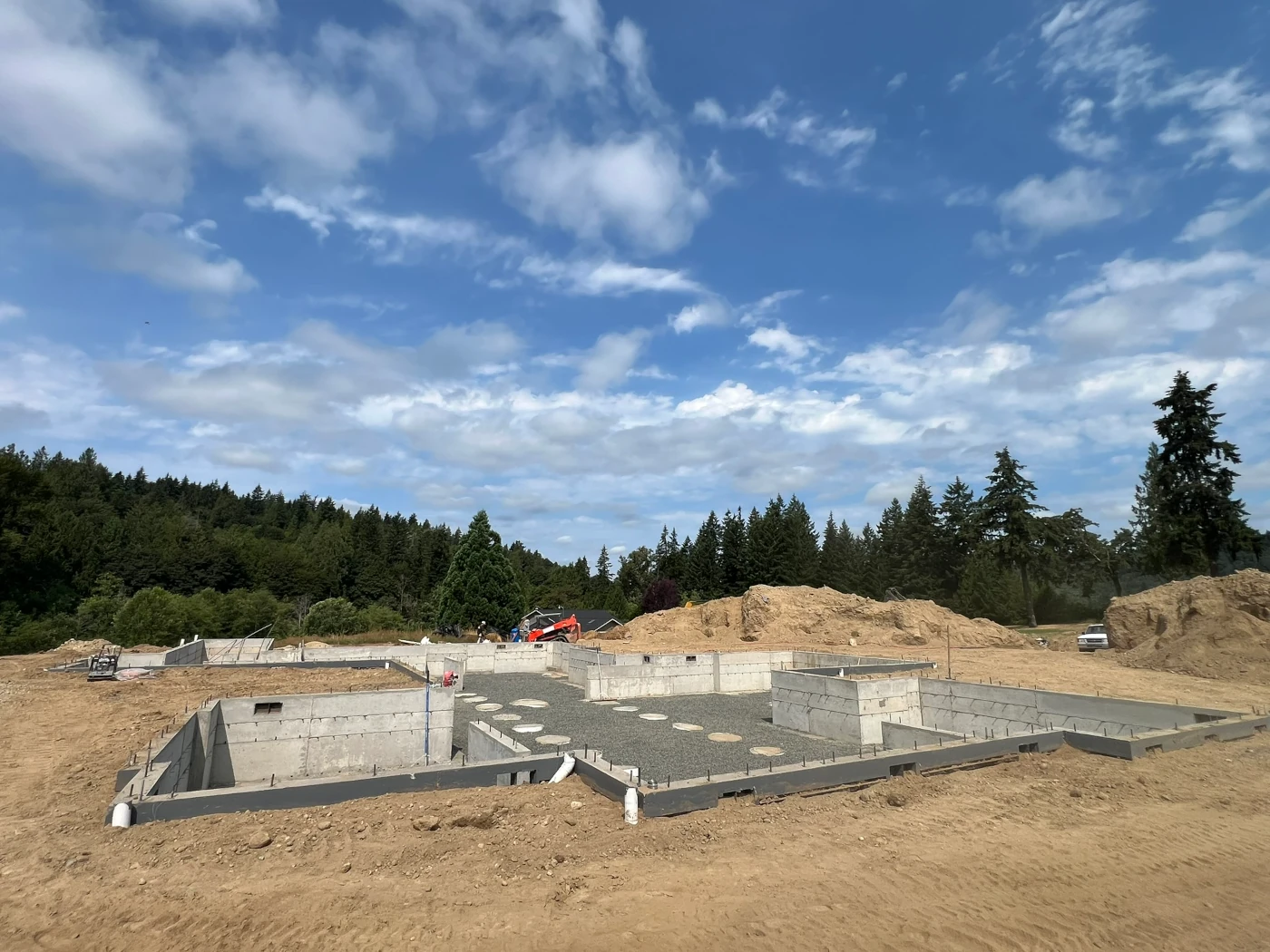 Crawlspace foundation walls with anchor bolts and concrete pier pads set on compacted gravel