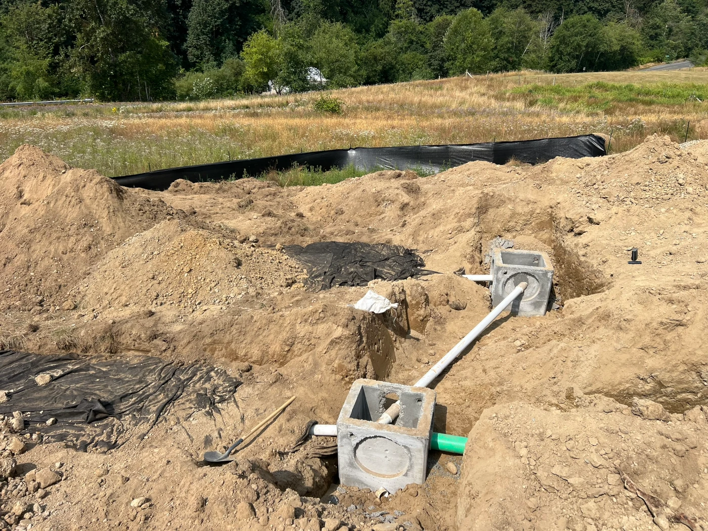Concrete catch basins connected to PVC and green storm pipe with silt fence protecting the site perimeter