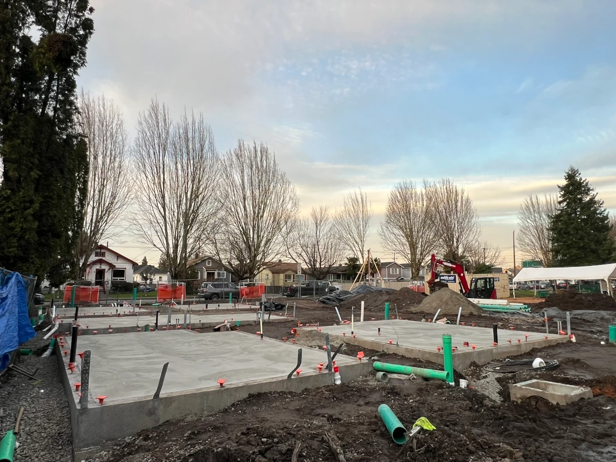 Freshly poured concrete slab foundations with plumbing rough-in on a residential job site