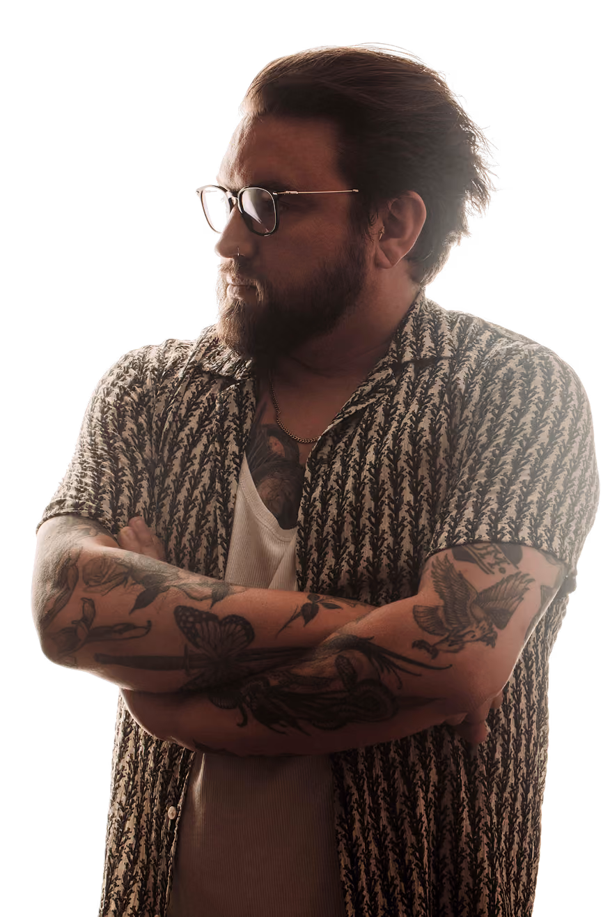 Alex Day, tattoo artist at Sonder Tattoo & Piercing London, arms crossed showing botanical and eagle tattoo sleeves.