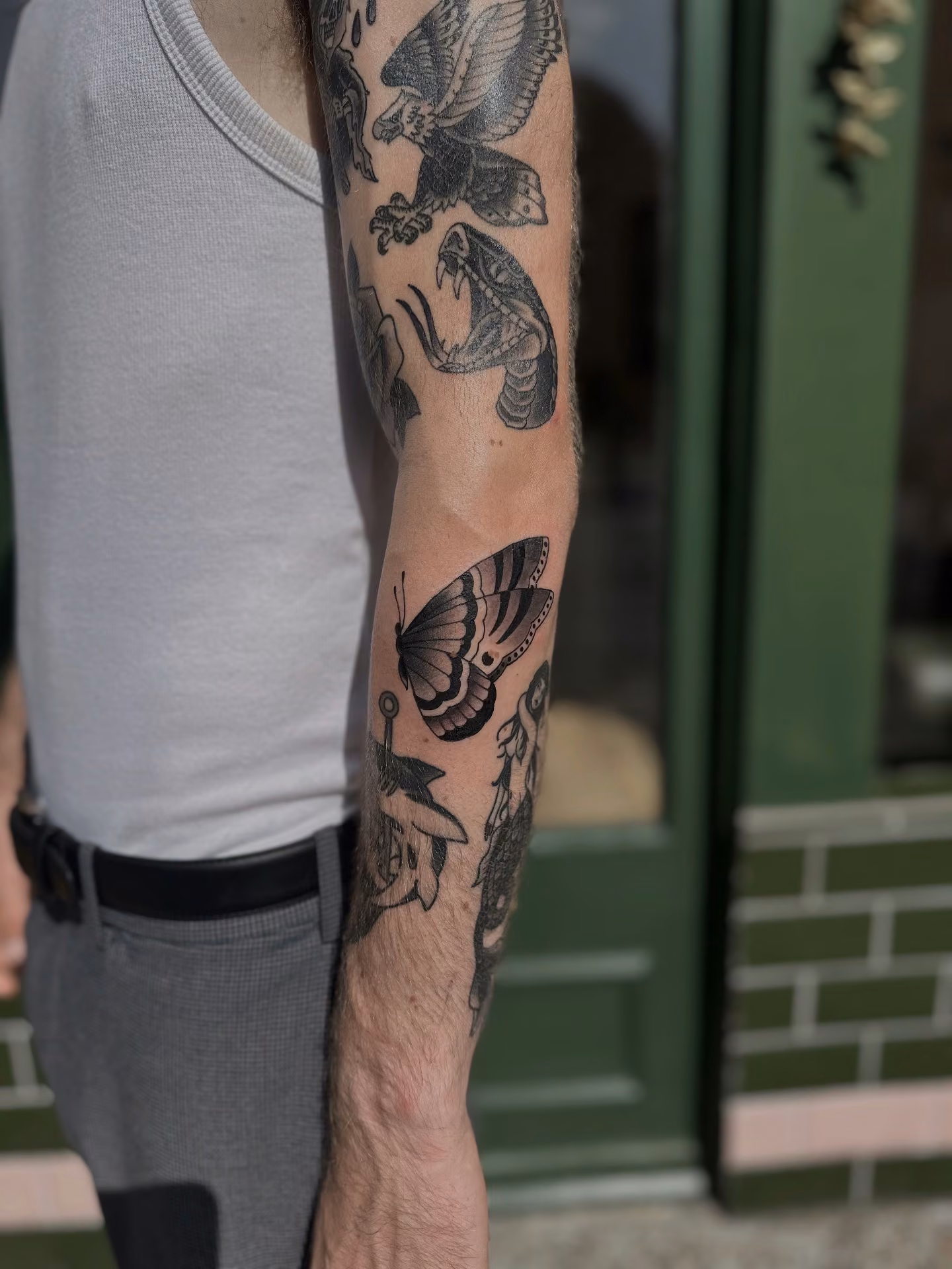 Traditional eagle, snake and moth tattoo sleeve on an arm