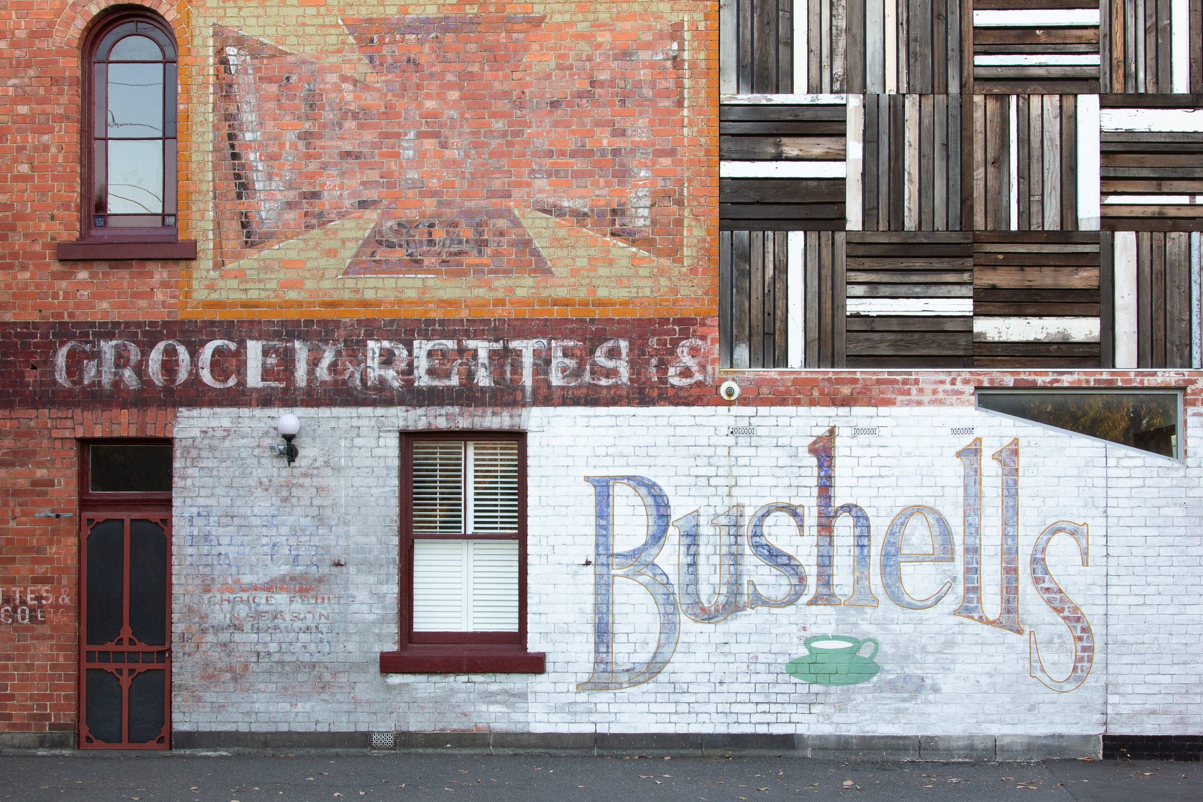 Layered ghost signage for a grocer and Bushells on a Melbourne brick wall