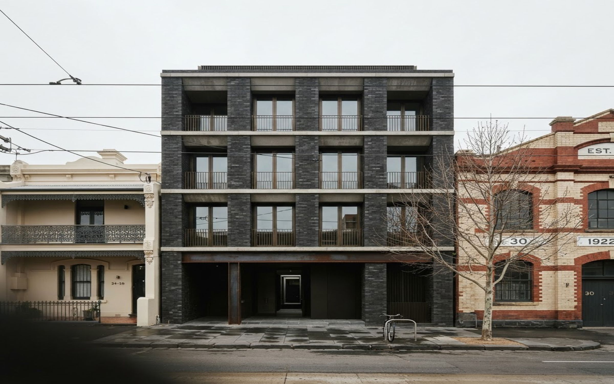 Lintel: a dark-brick residential building between a Victorian terrace and a polychrome brick warehouse in Melbourne's inner north