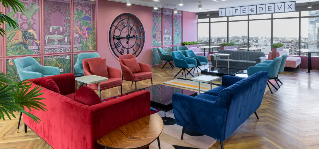 Modern lounge with colorful velvet chairs, sofas, large clock, tropical wall art, and city view windows.