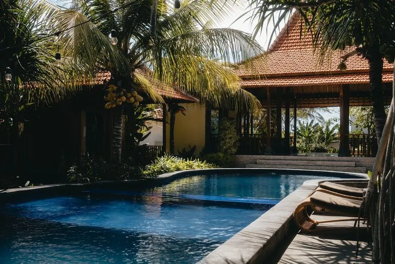 Balinese resort with a swimming pool and palm trees.