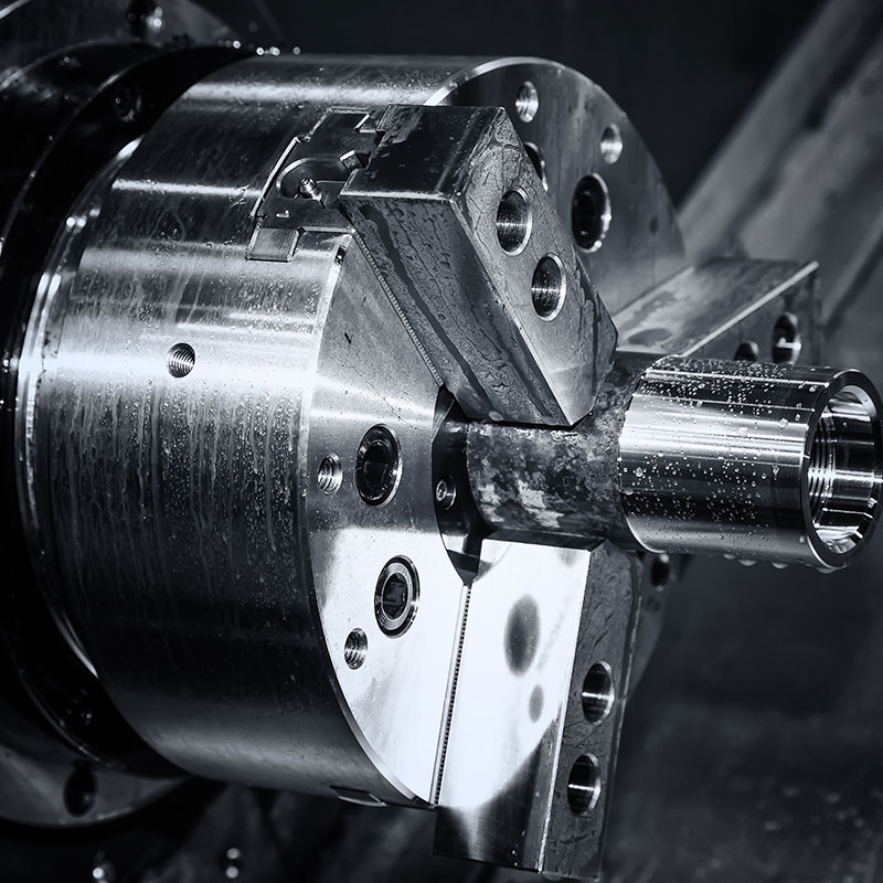 Nahaufnahme eines rotierenden Metallspannkopfs mit eingespanntem zylindrischem Werkstück.