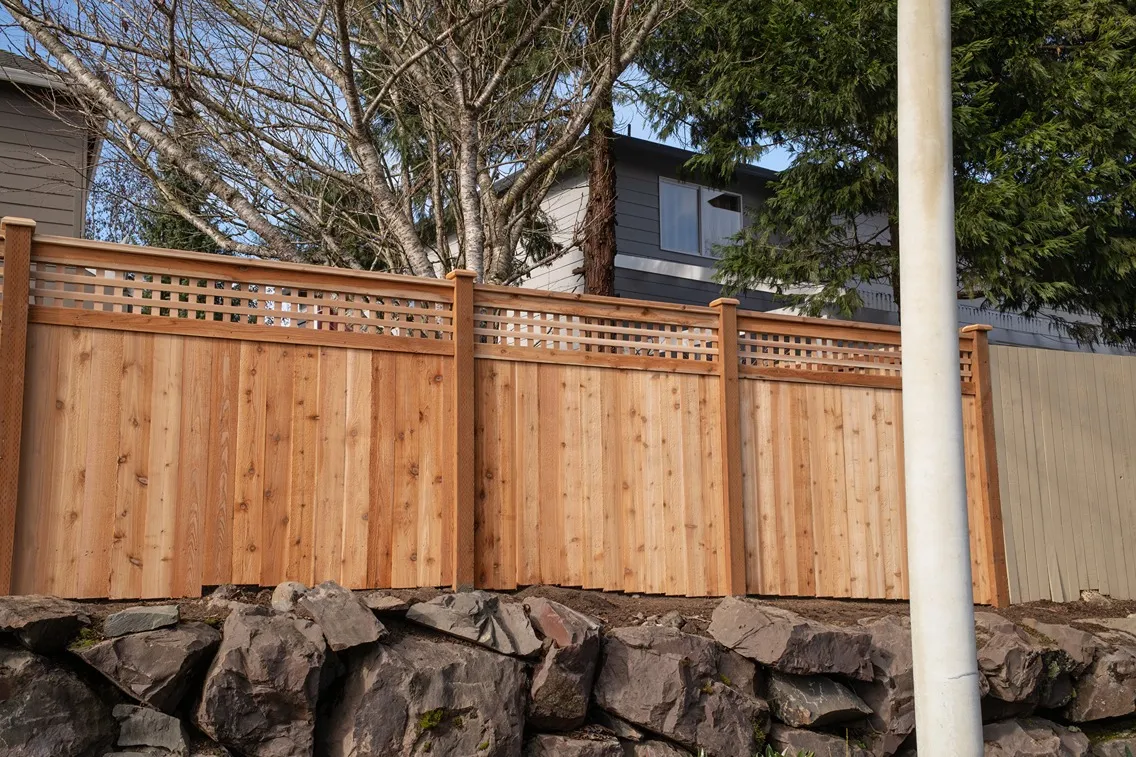 A cedar fence built atop of a rocky retaining wall in a residential area in Vancouver
