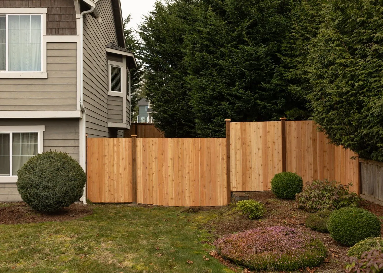 Cedar fence installed near shrubs and trees in a garden of a Vancouver property