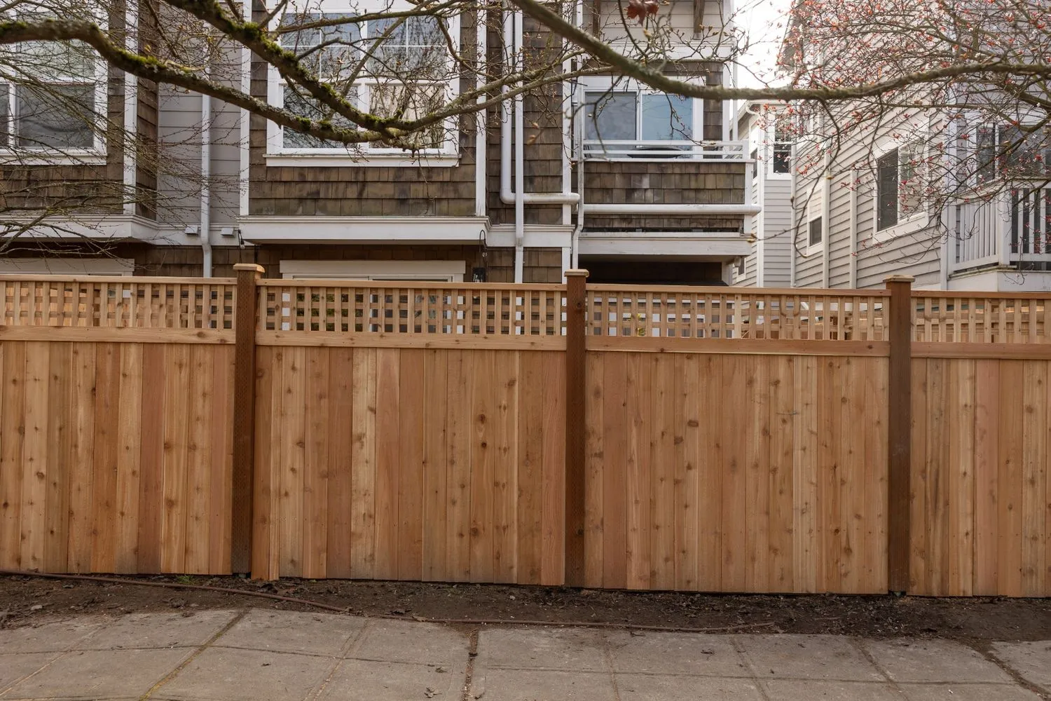 Wooden privacy fence with posts built in front of a pre-1980 home