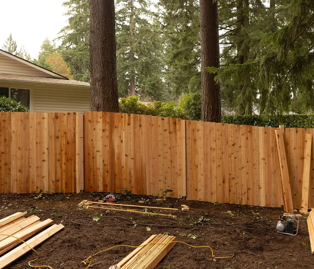 A wooden fence during installation process in a sloped lot