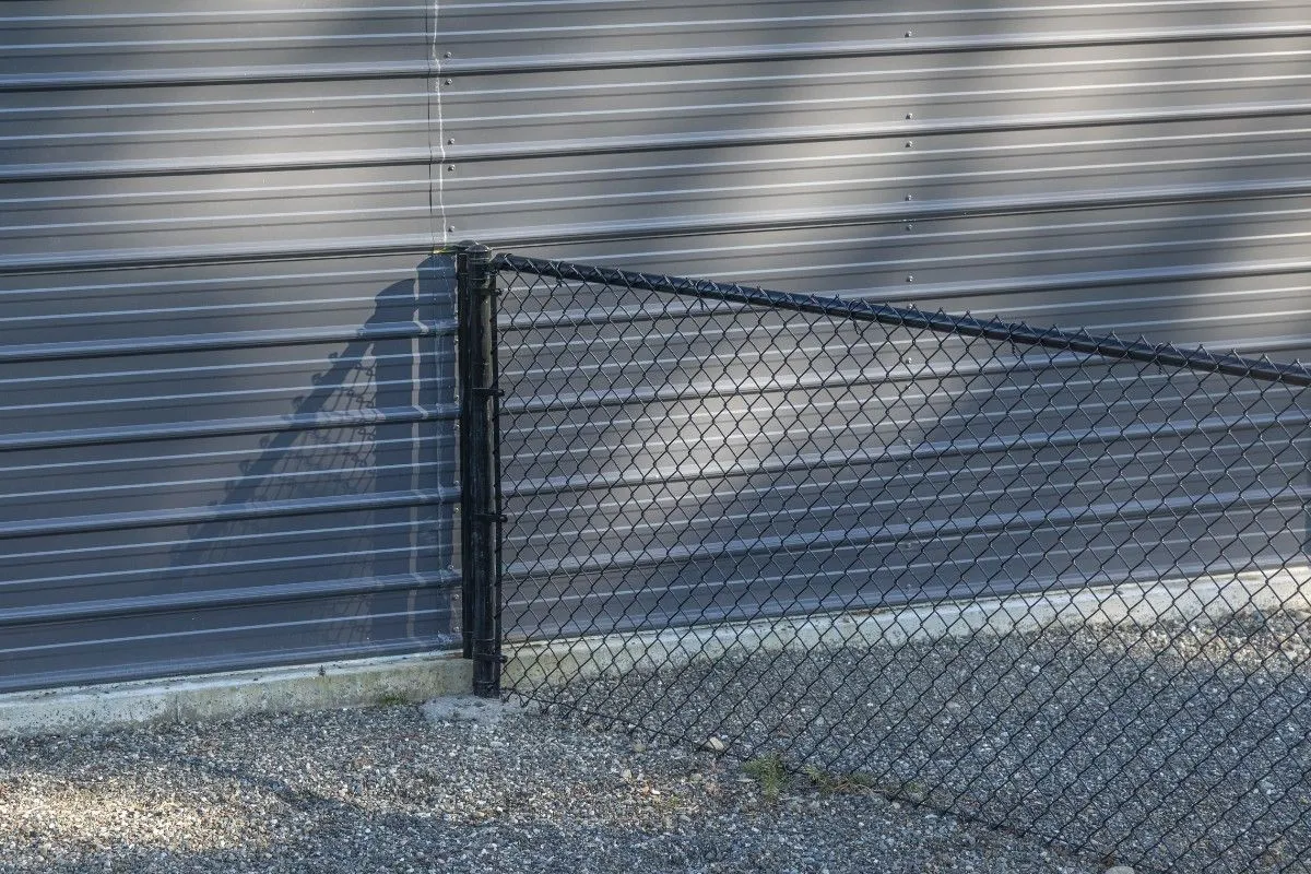 Chain link fence post installed beside a wall of a container van toolshed in Portland