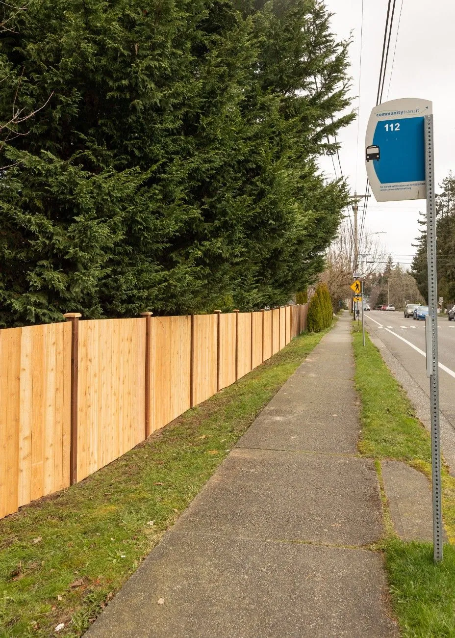 A wooden privacy fence in Vancouver facing the sidewalk and street signs