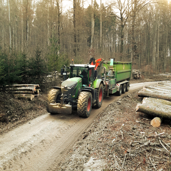 Traktor mit Hacker und Container auf einem Waldweg