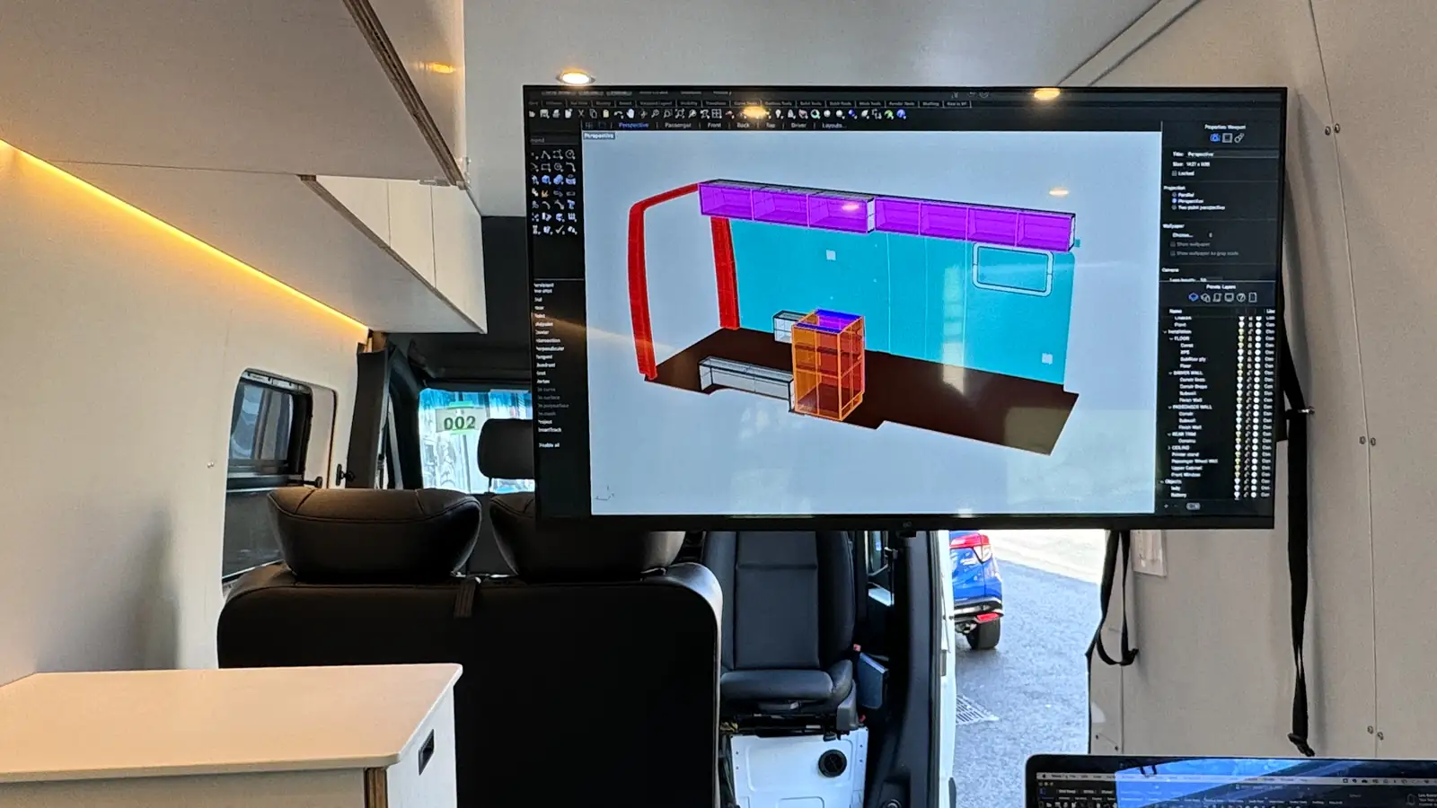 Large TV inside a van under construction displaying a 3D CAD model of the interior layout