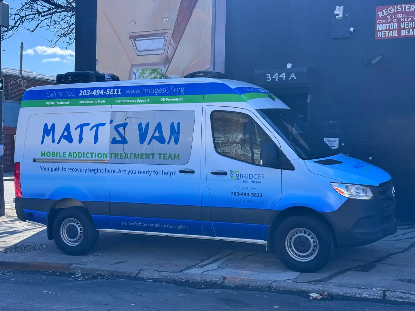 Bridges Healthcare MATT'S VAN Sprinter, front three-quarter view showing its white, blue and green wrap