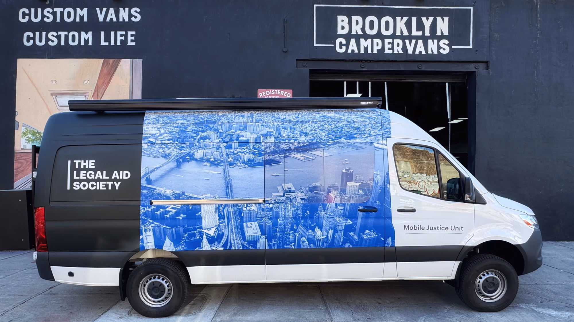Legal Aid Society Mercedes Sprinter with a New York skyline wrap parked outside Brooklyn Campervans
