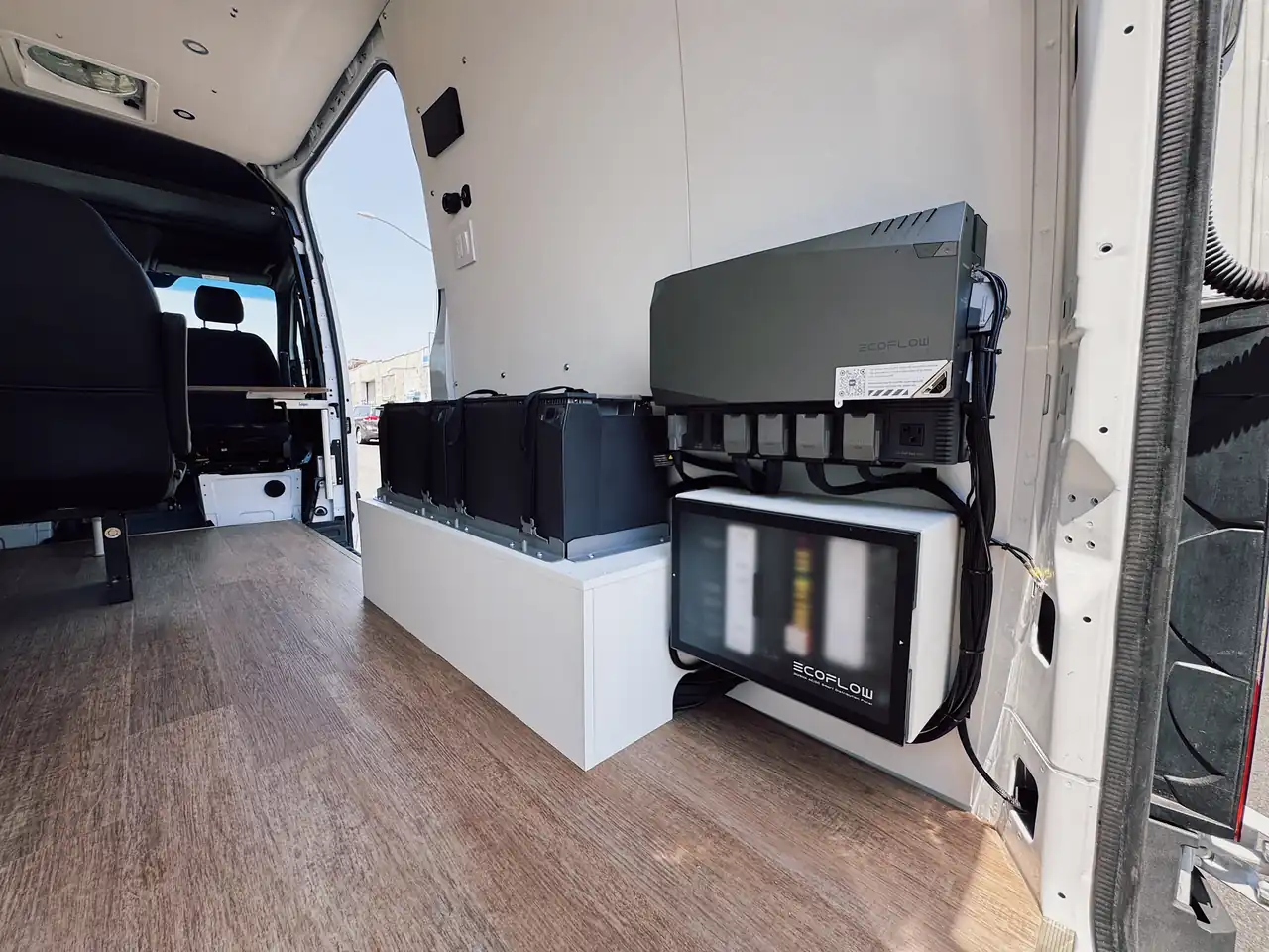 Mercedes Sprinter electrical bay with four batteries on a white bench, EcoFlow inverter and distribution panel