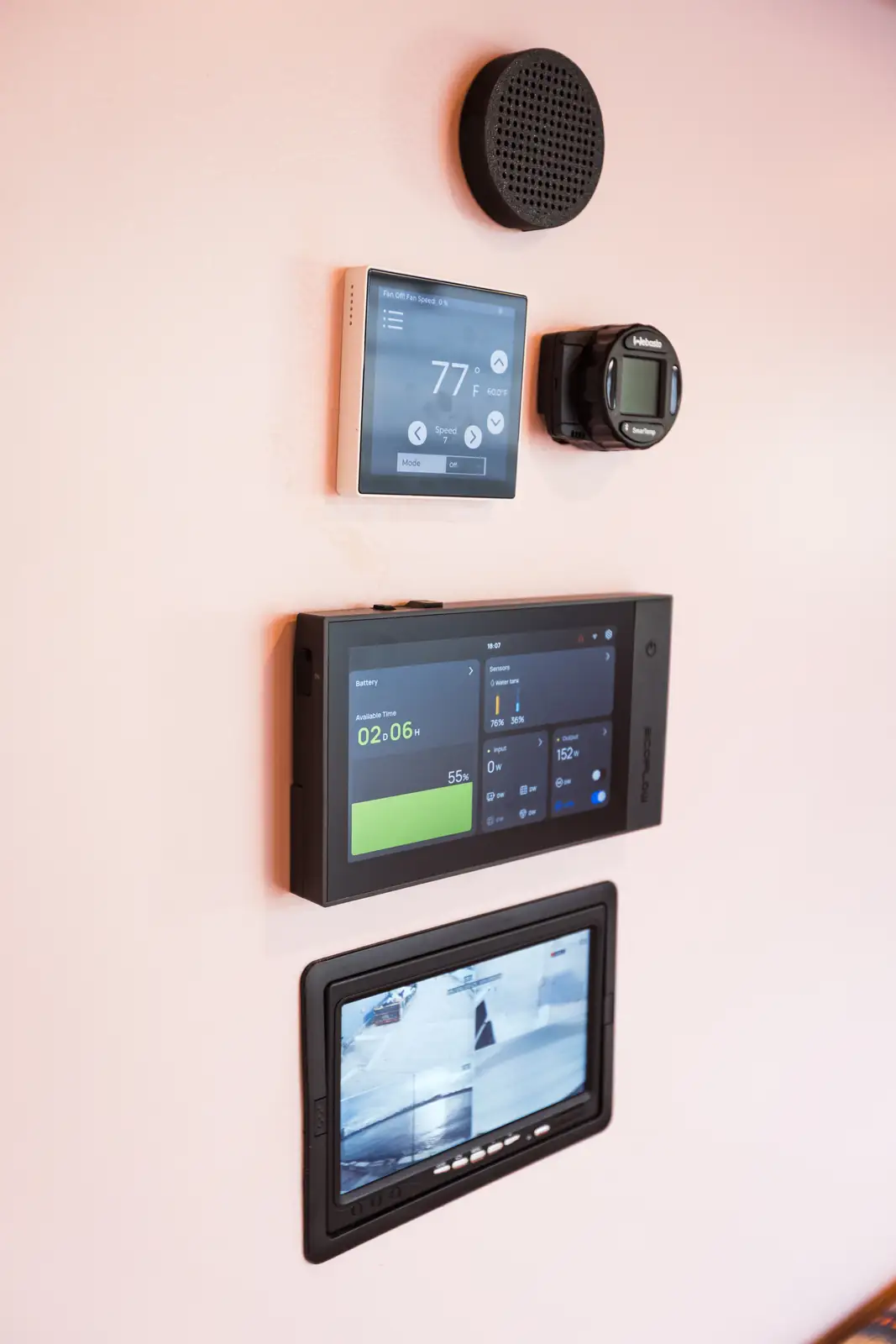 Control panel on a pink van wall with speaker, 77°F thermostat, EcoFlow-style power screen and rear camera monitor