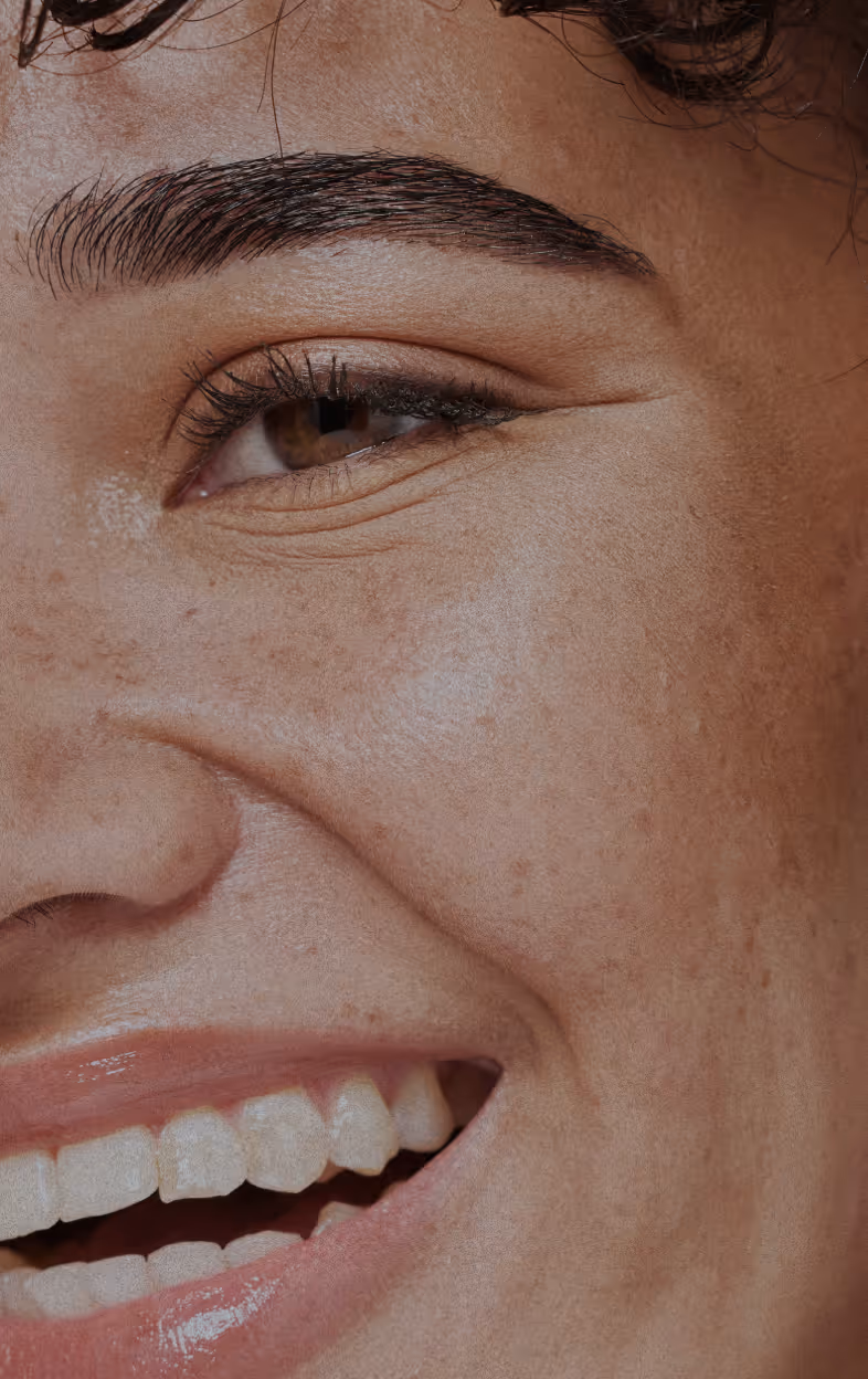 Close-up of a person’s lips, nose, and freckled skin with a natural glossy finish.