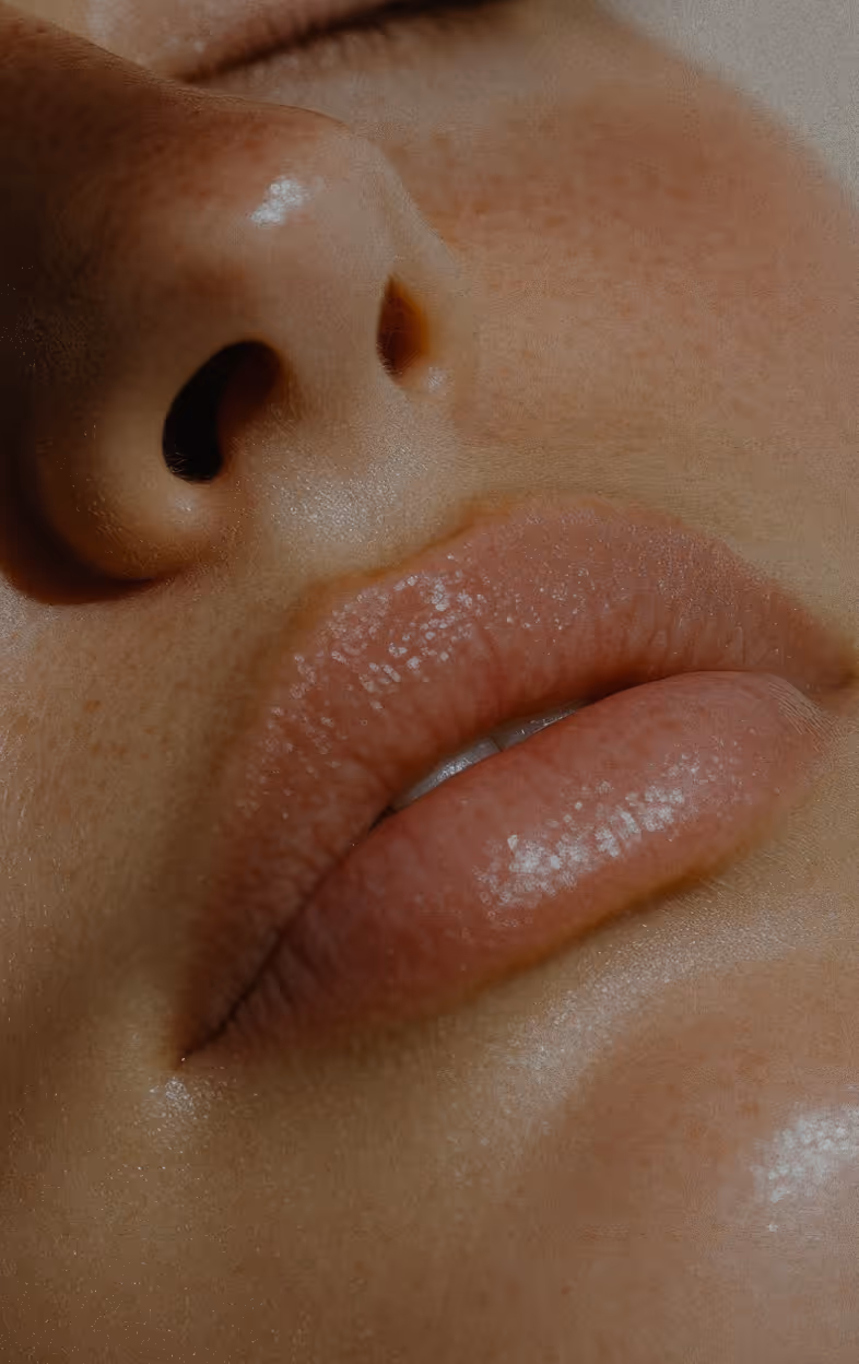 Close-up of a person's nose, lips, and surrounding skin with visible freckles and natural texture.