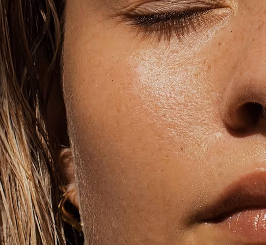 Close-up of a person's face with closed eyes, showing smooth skin and part of wet hair.