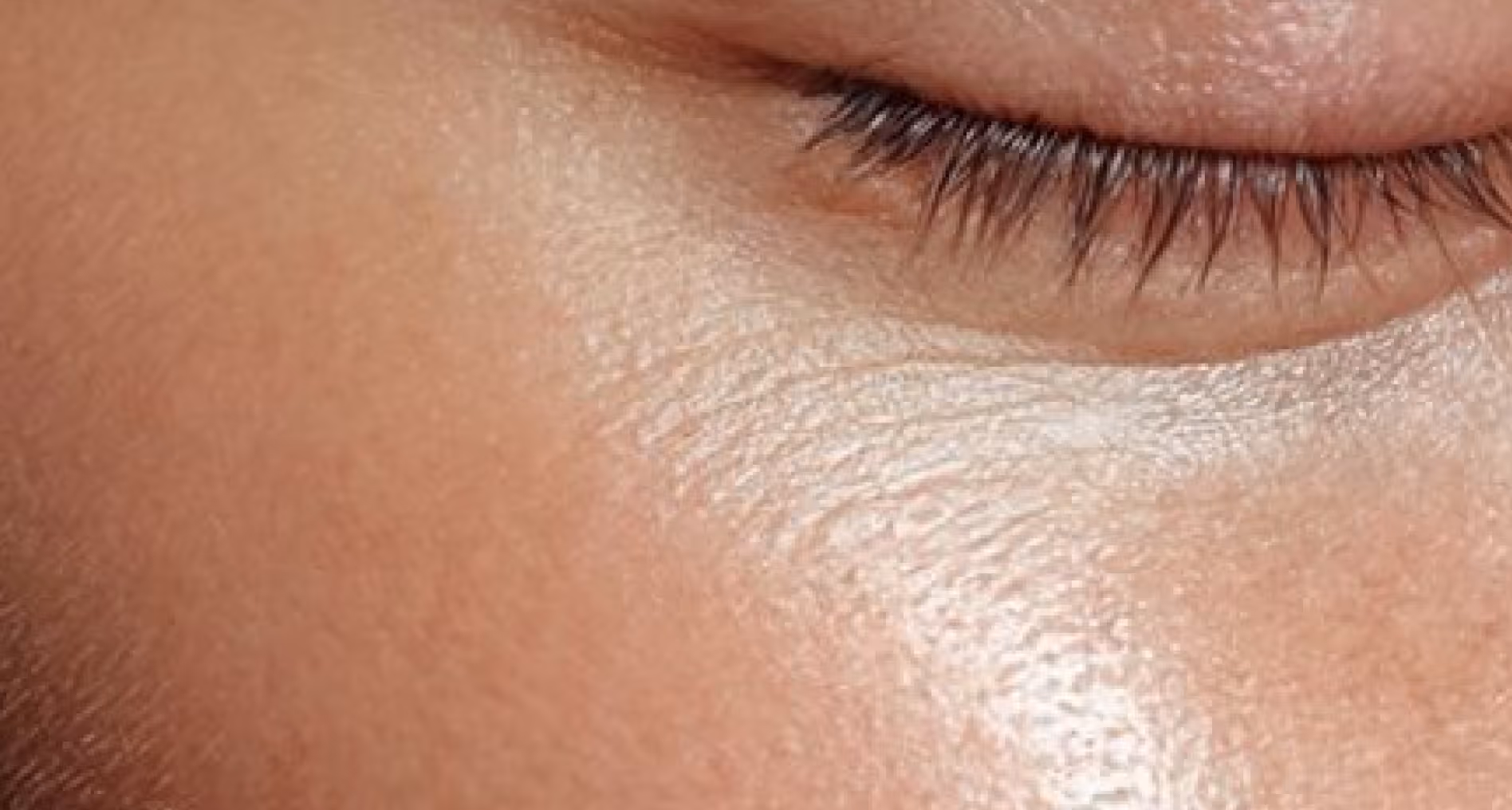 Close-up of closed eye with visible eyelashes and smooth skin texture around it.