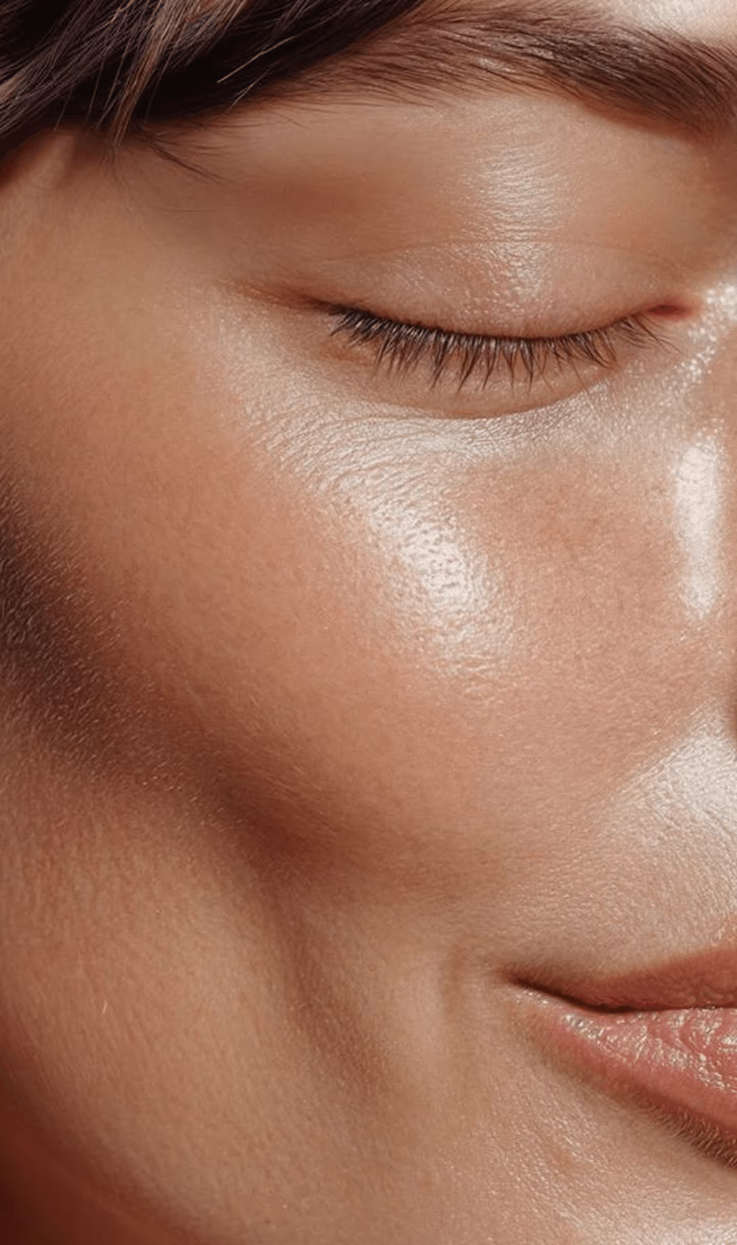 Close-up of a person's smooth, glowing skin with closed eye and slight smile.