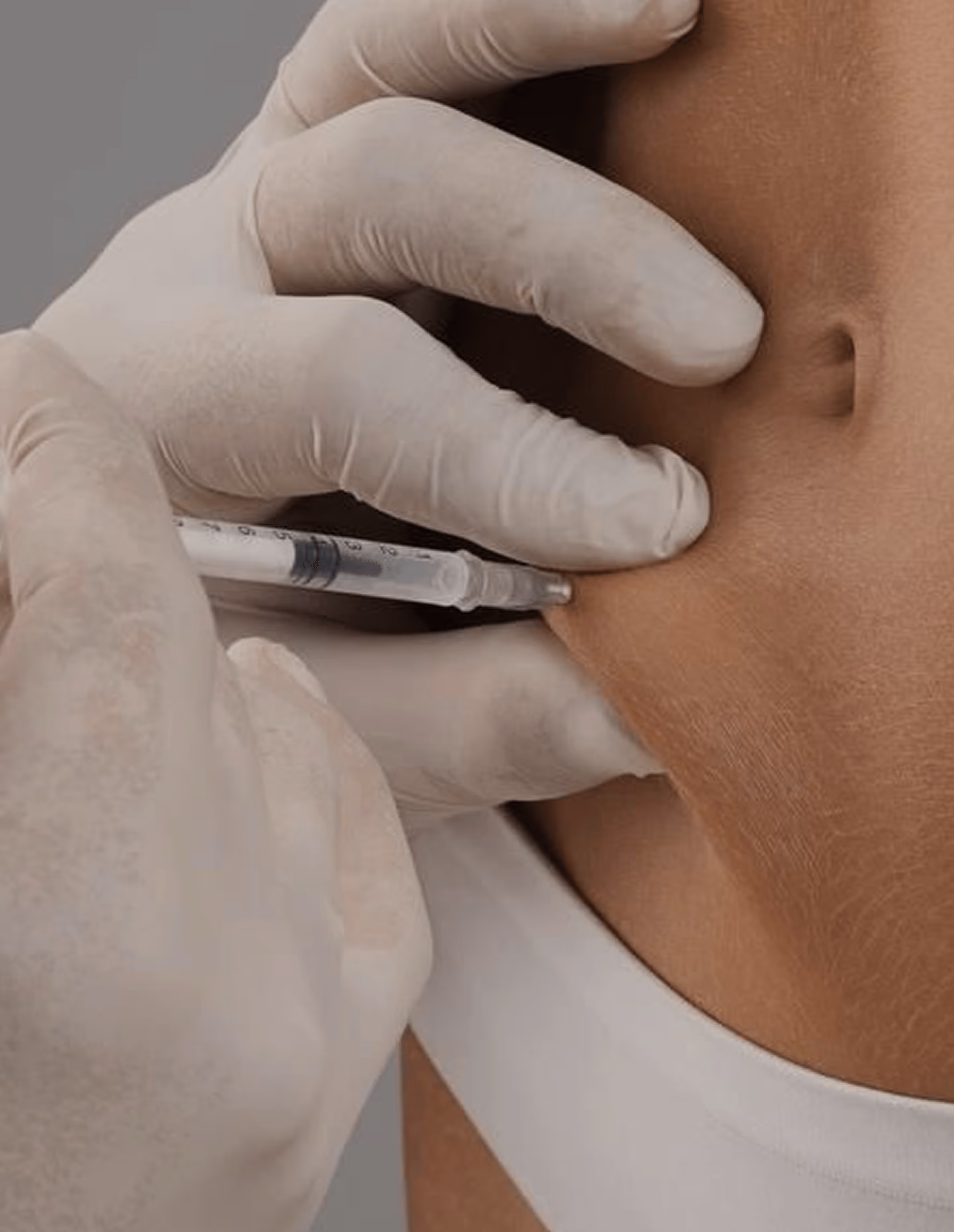 Gloved hand injecting a syringe into the side of a person's lower abdomen near white clothing.