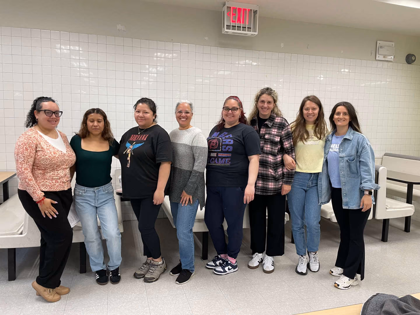Group of eight school staff members posing together in cafeteria