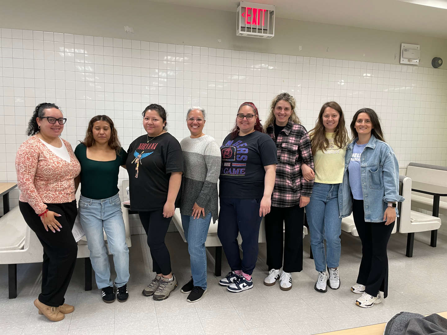 Group of eight school staff members posing together in cafeteria