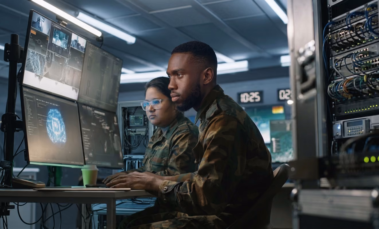 Mario and Maria working at a wall of monitors in a control room