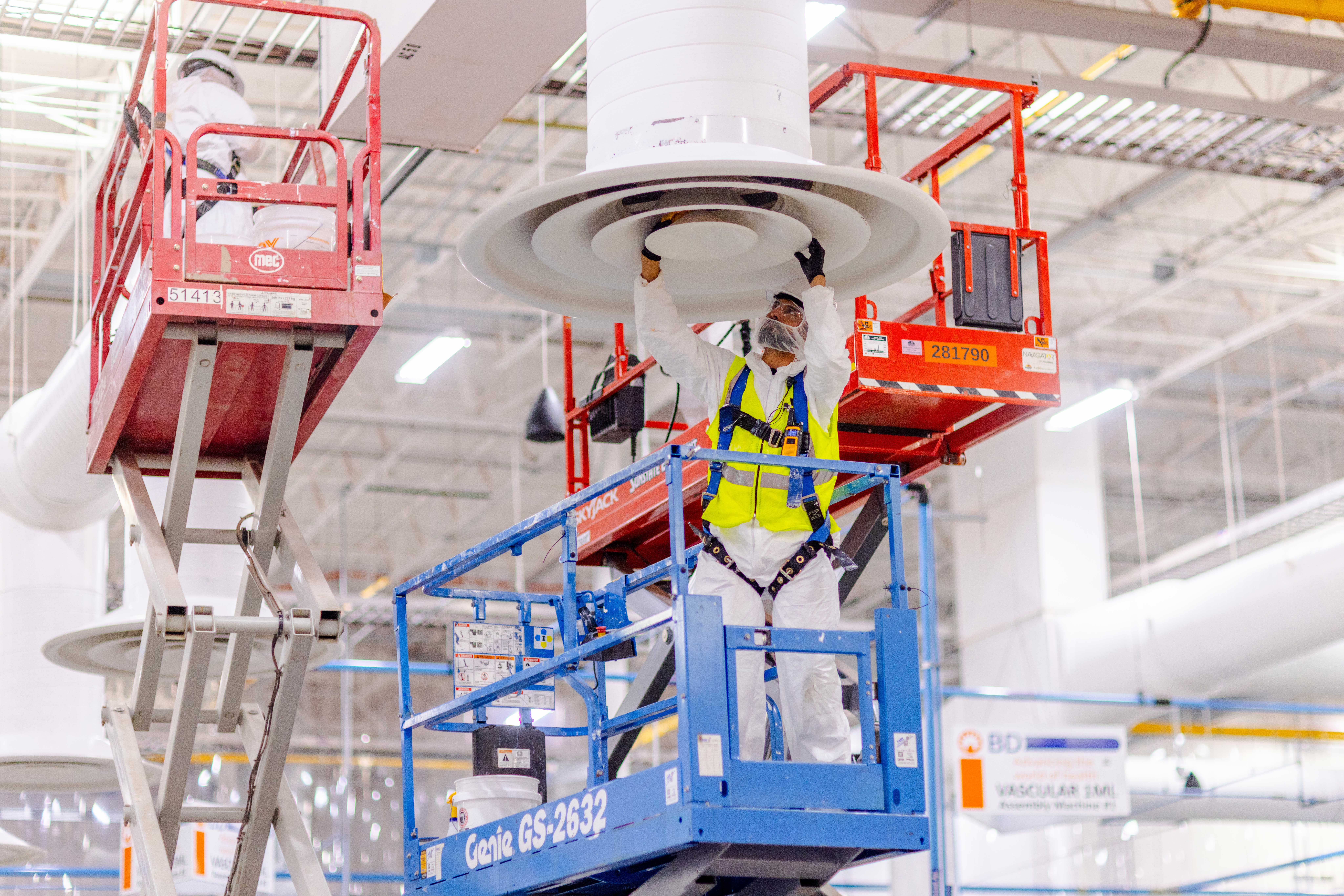 Maintenance worker on ladder performing ceiling panel work