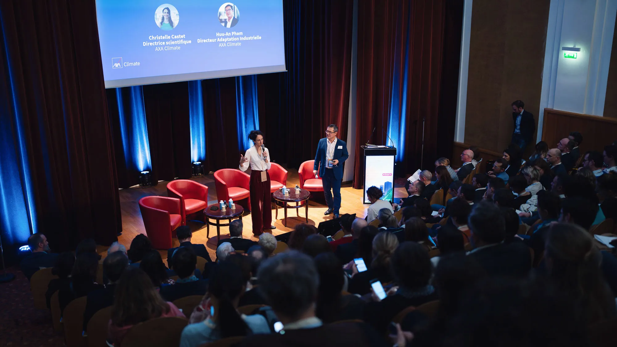 Caméra sur trépied face à une scène de conférence