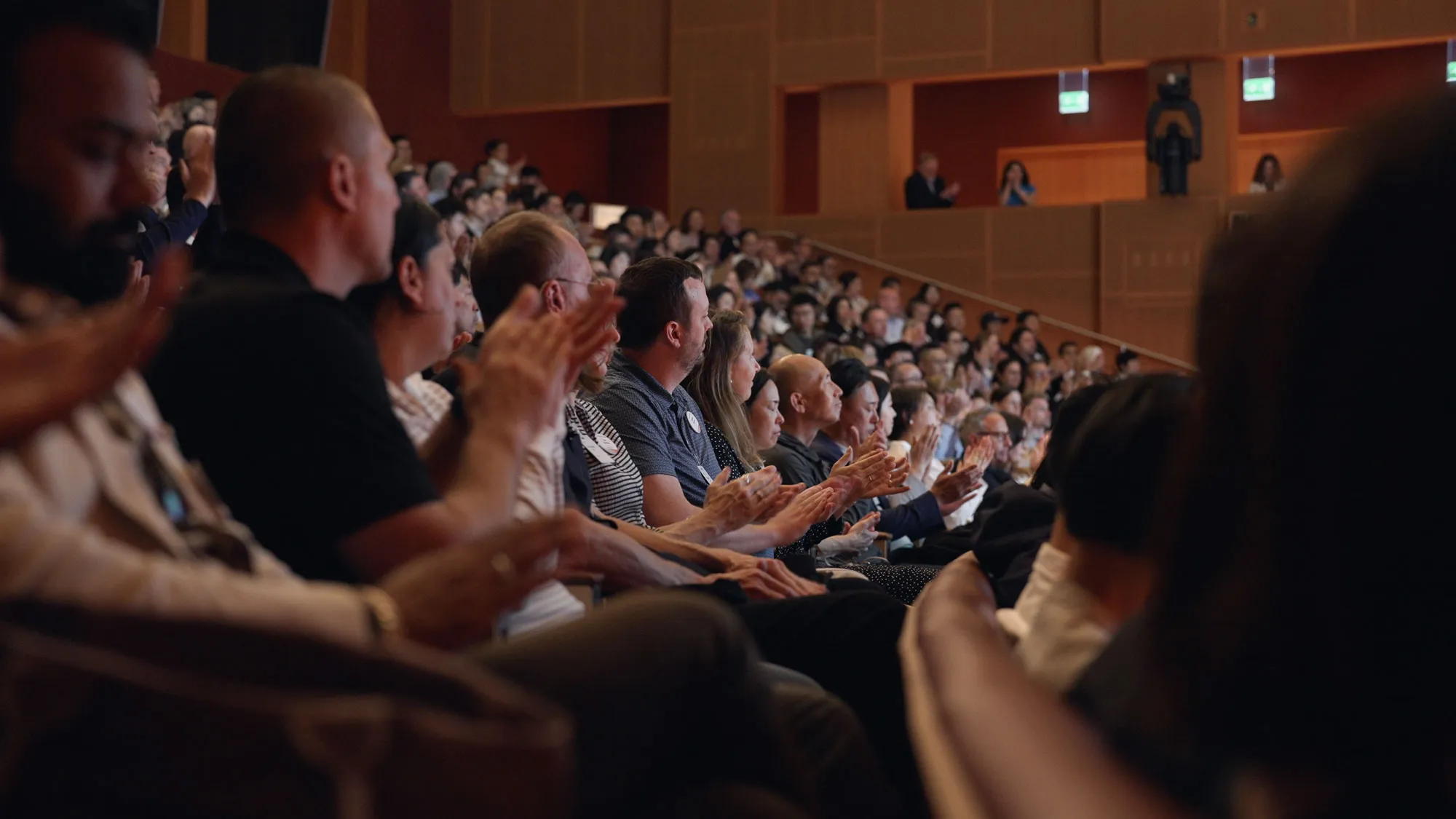Le public applaudit depuis les gradins d’un auditorium pendant un événement