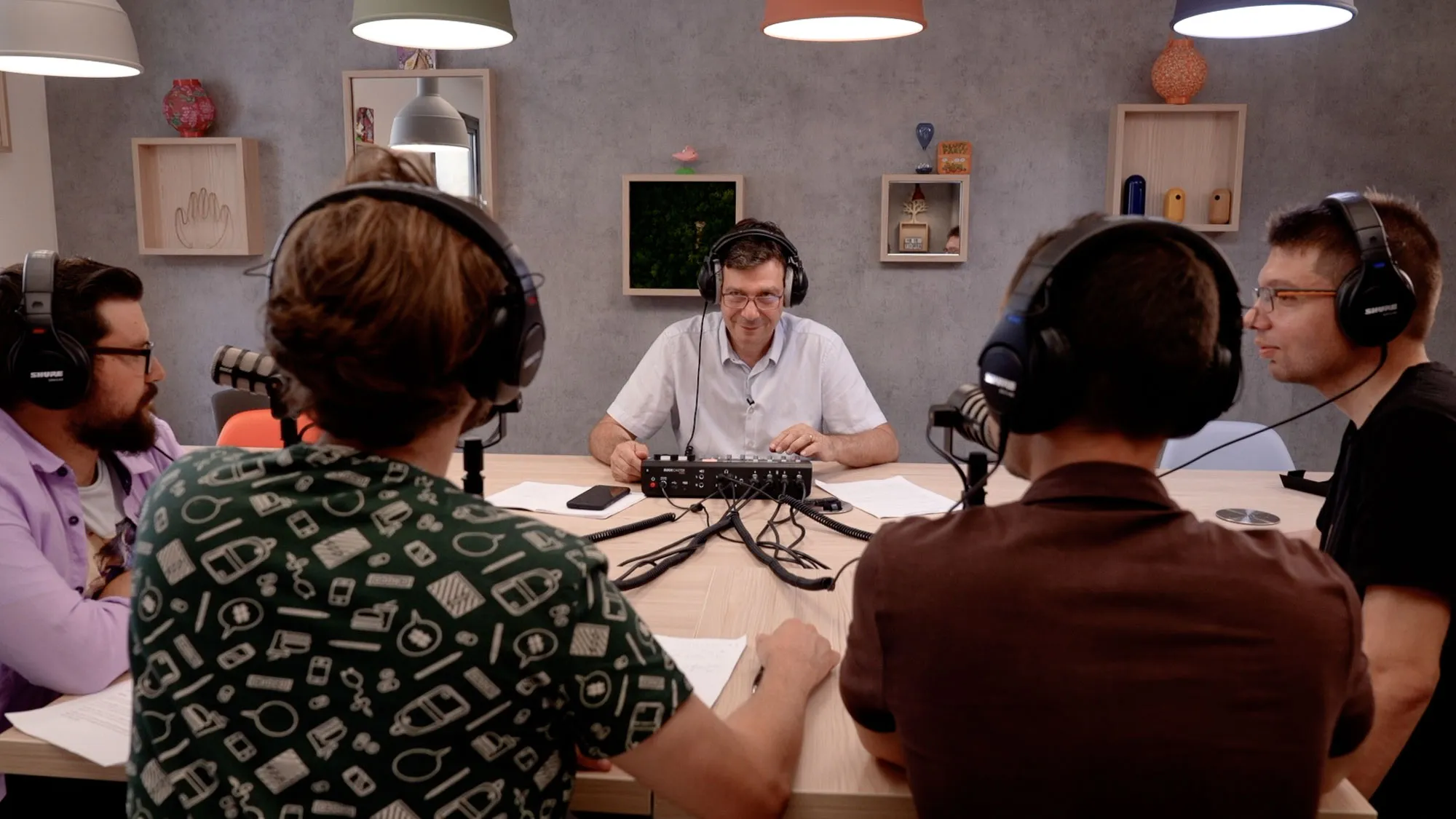 Cinq personnes autour d’une table lors d’un atelier radio, casques sur les oreilles et micros devant elles