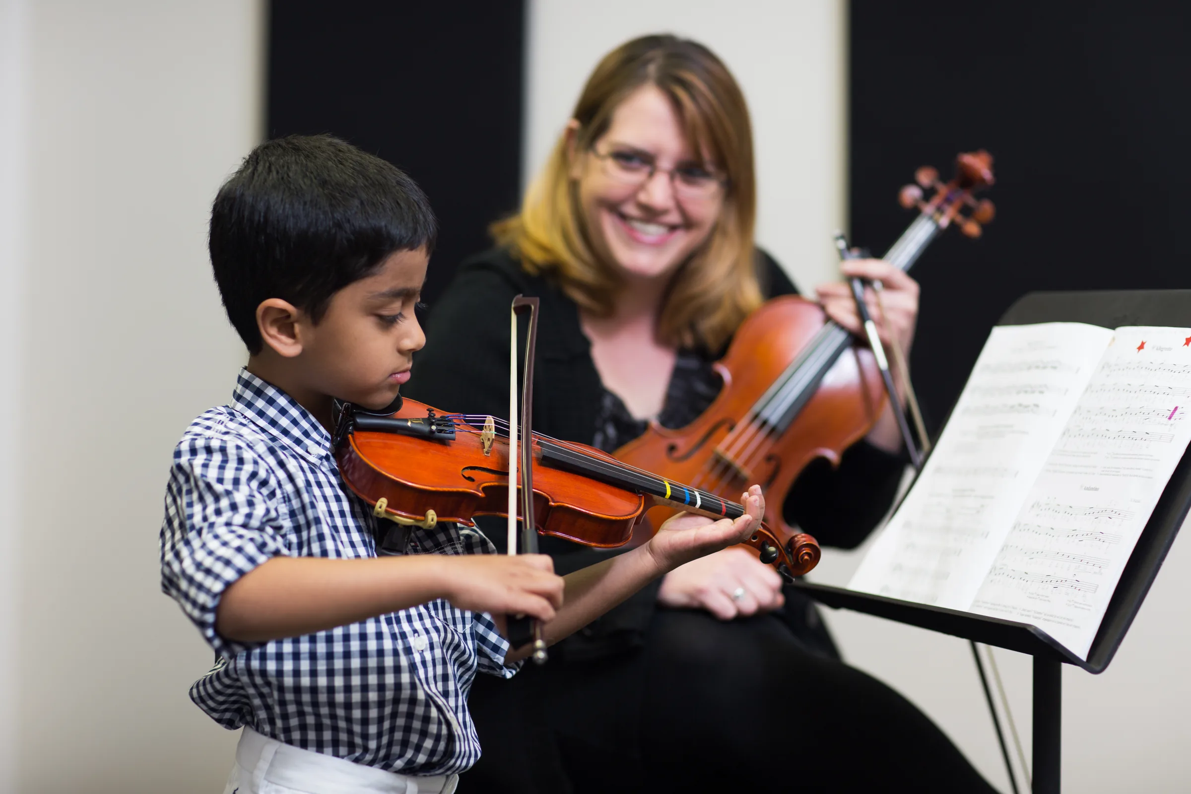 A young boy taking a violin lesson with his teacher.