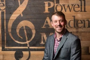 Male music instructor headshot in front of a Foundations Music Academy sign