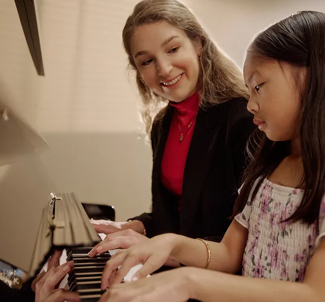 Music teacher helping a young student during a piano lesson