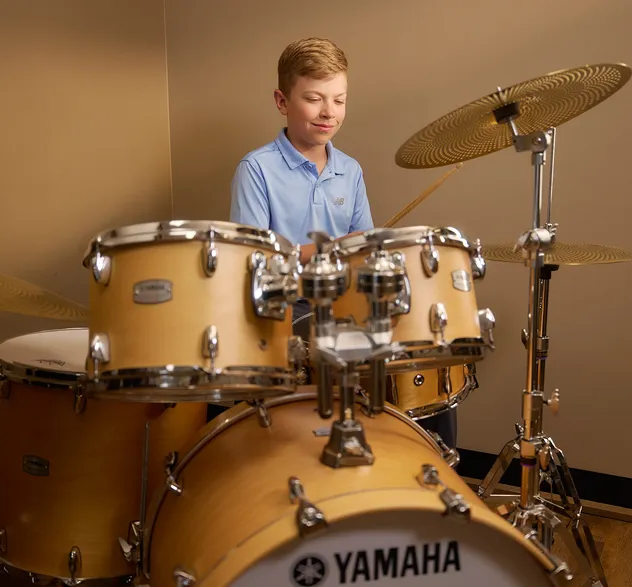 Young boy playing a drum kit during a music lesson