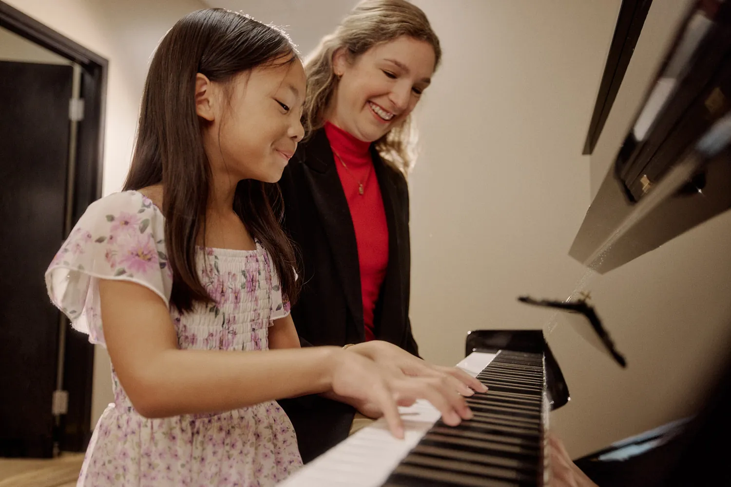 Young piano student and her teacher smiling together at the keyboard in Powell, Ohio