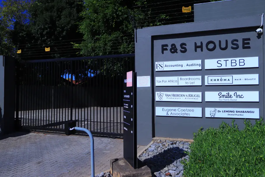 Entrance gate of F&S House with signage for various businesses including a dental practice and hair salon.