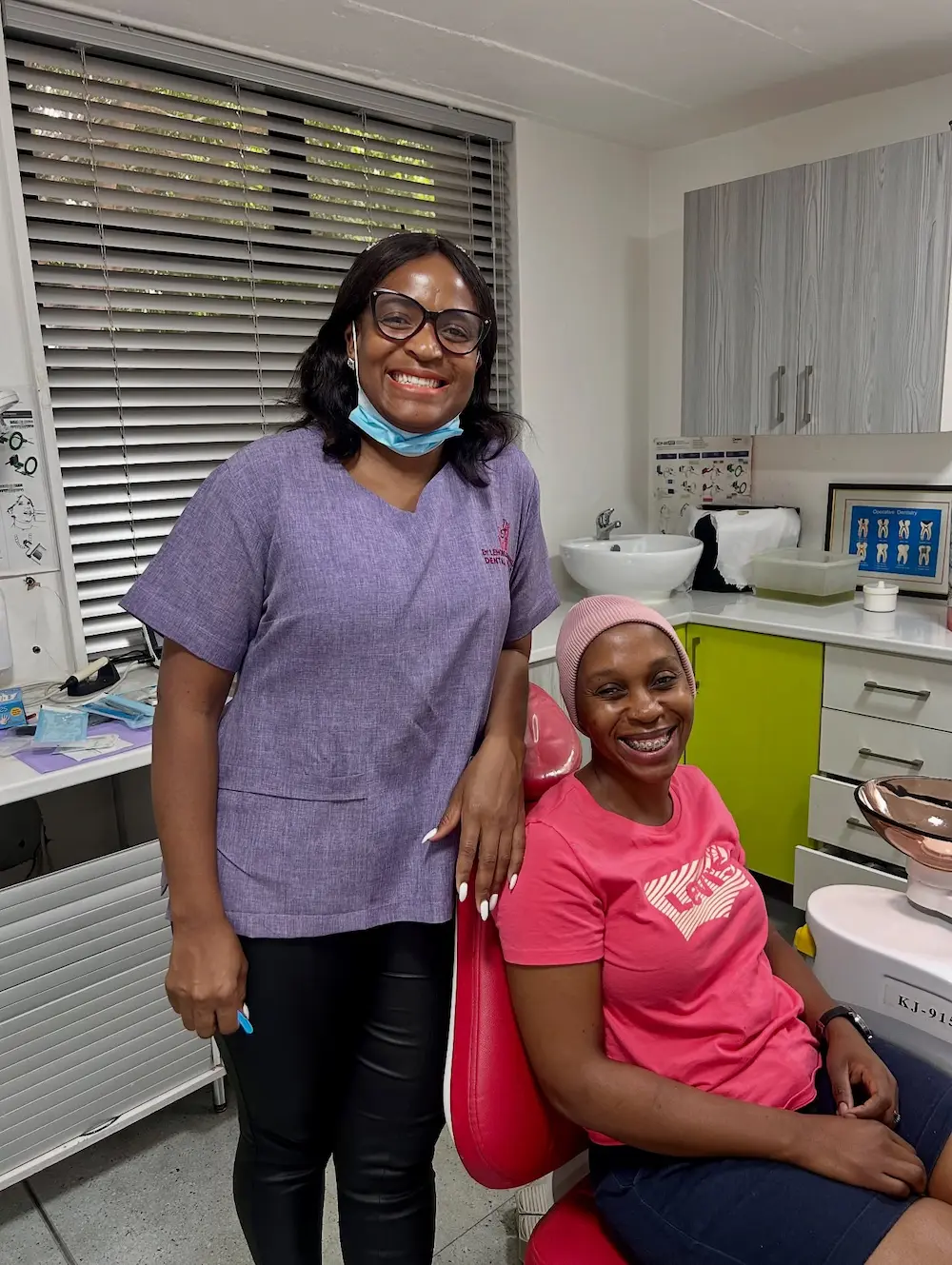 Smiling dental professional standing beside a happy patient with braces sitting in a dental chair.