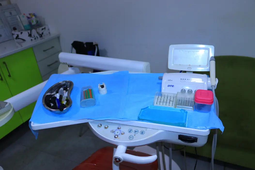 Dental tools and equipment arranged on a blue cloth on a dental chair tray in a clinic.