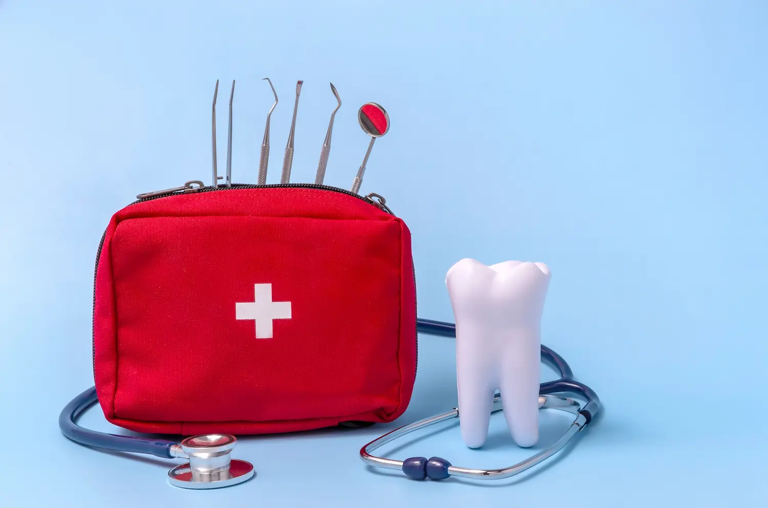 Red medical bag with dental tools, a stethoscope, and a large tooth model on a blue background.