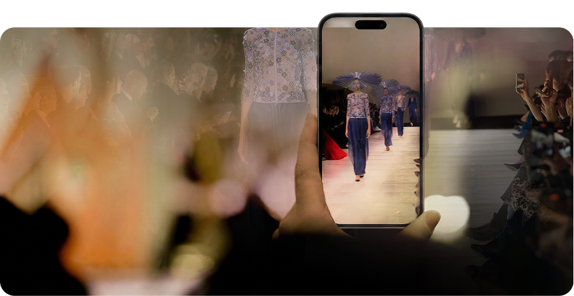 Phone filming a model on the runway from the front row of a fashion show