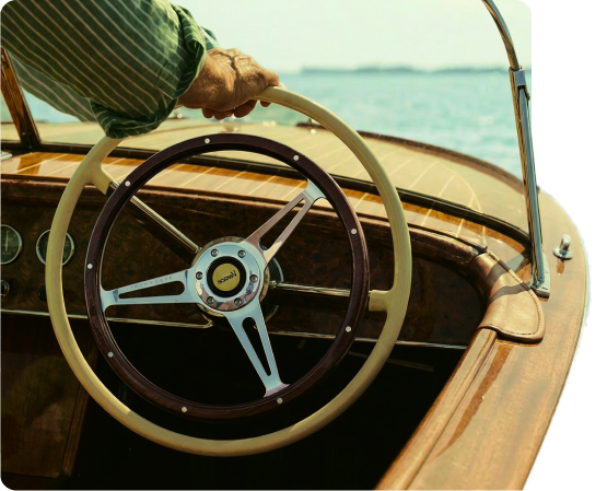Steering wheel of a classic wooden motorboat on open water