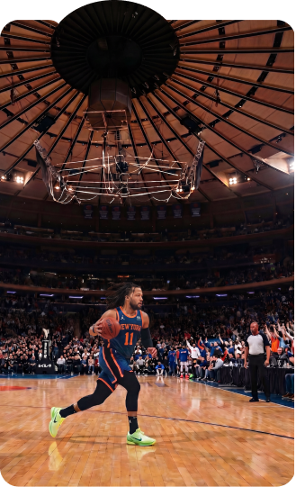 Basketball player on court beneath the domed roof of a packed arena