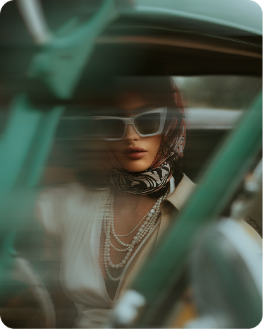 Woman in sunglasses and pearls seen through a car window