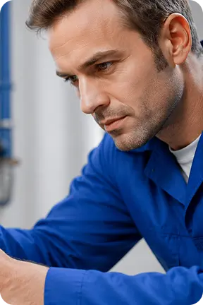 Focused man in a blue work shirt looking down, possibly working on a task.